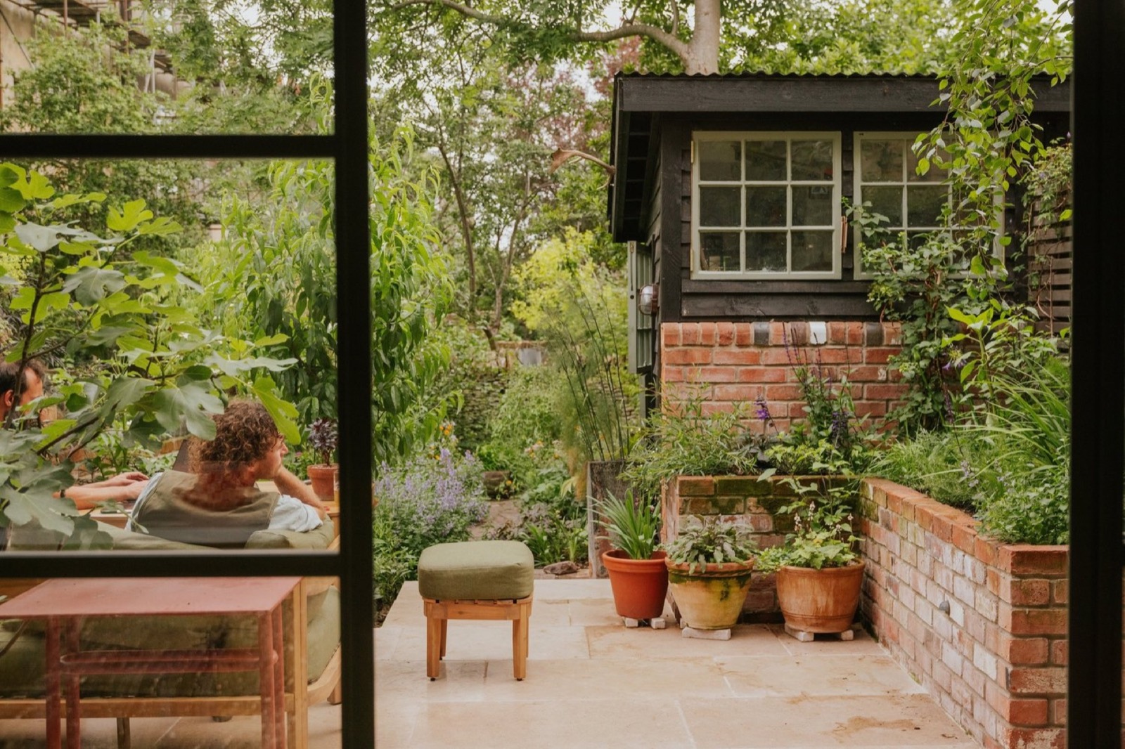 Richmond Rd, Bristol: a level terrace, potted figs and layered planting around a garden office, seen from the kitchen